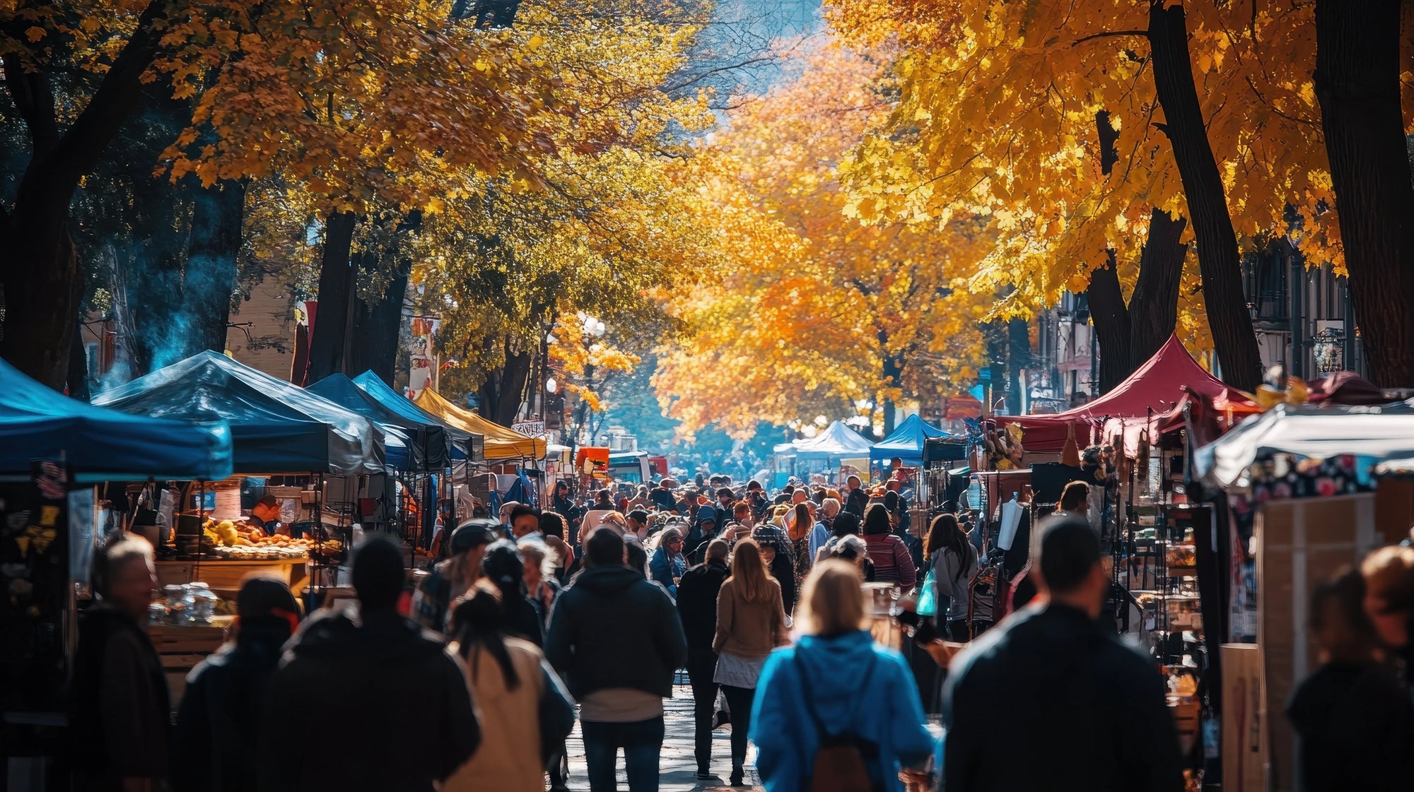 A bustling autumn street market lined with colorful vendor tents and a crowd walking down the center.