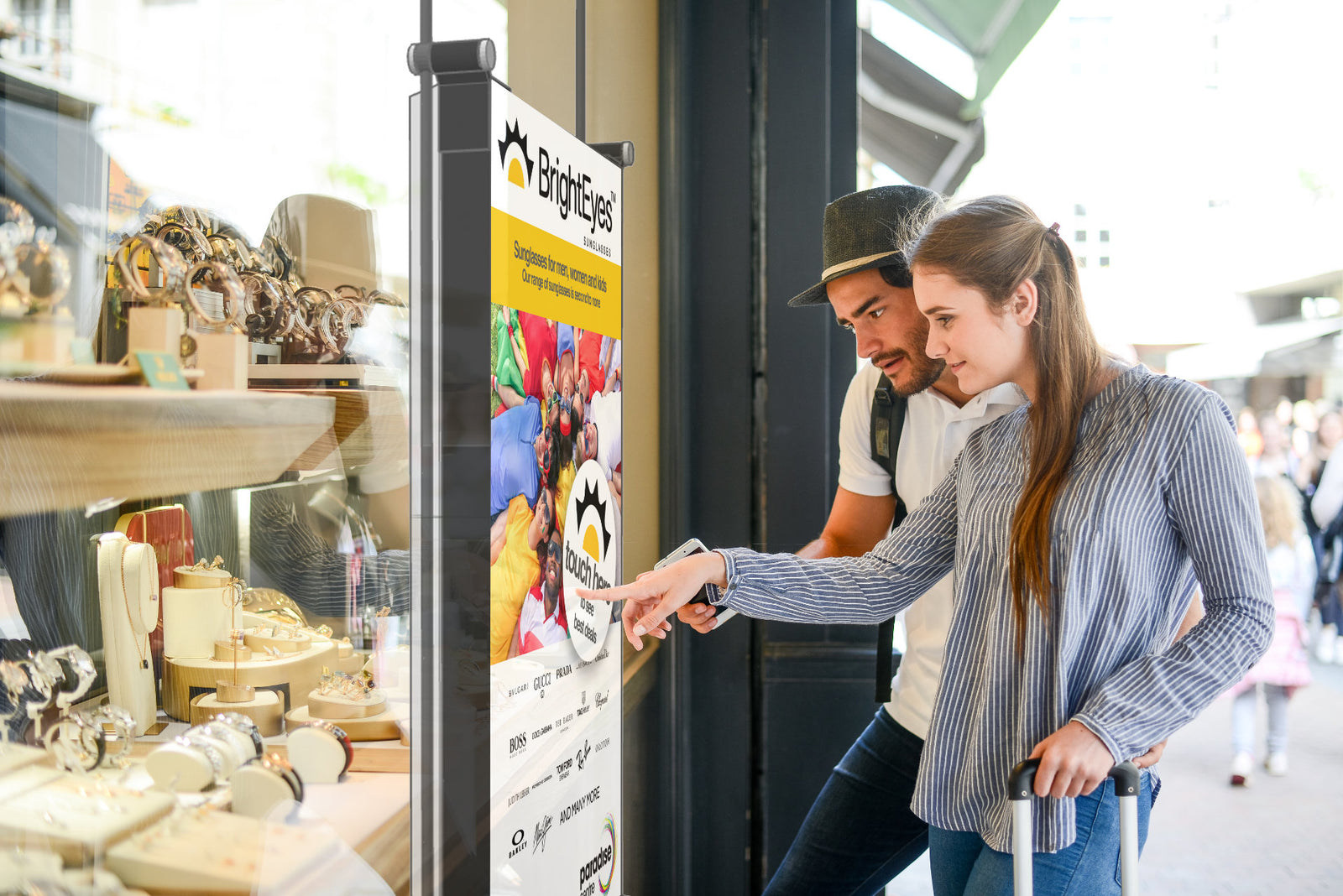Two people using a digital menu board inside a storefront.