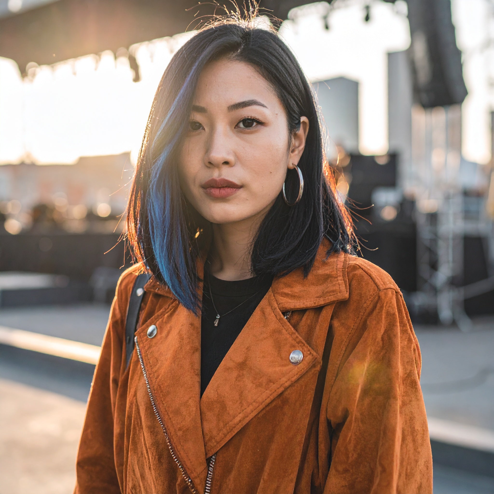 Woman with blue hair wearing an orange jacket outdoors