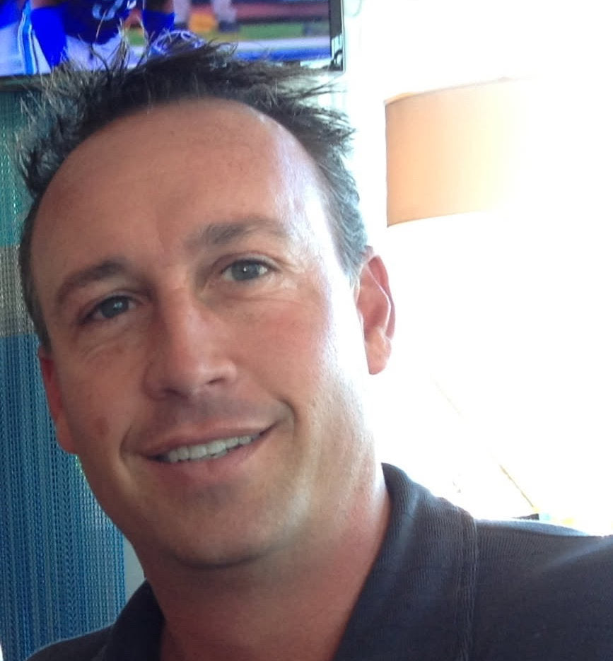 Man smiling in a casual setting with a blurred background